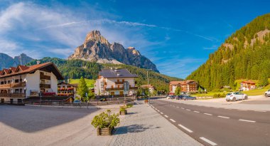 Güneşli bir günde büyülü Dolomite tepeleri, ormanlar ve oteller üzerine panoramik manzara ve mavi gökyüzü, Colfosco, Corvara, Puez-Geisler, Puez-Odle Doğa Parkı, Güney Tyrol, İtalya