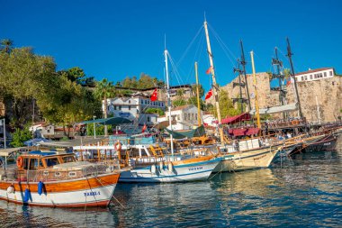 Antalya şehir merkezindeki Akdeniz sahili, plaj ve eski deniz manzarası ve geçmişten gelen bir korsan yelkenliye benzeyen büyük bir tur teknesi, Antalya, Türkiye.