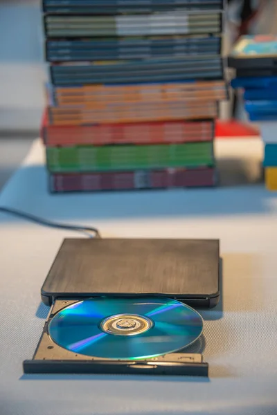 Compact stylish video player for CD and DVD disks with a pile of many TV series movie discs in background