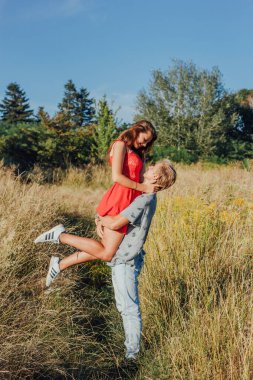 Sahada yürüyen mutlu bir çift. Adam kızı kollarında tutuyor..