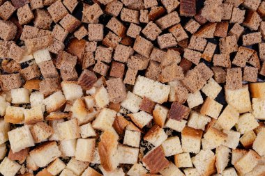 Koyu arkaplanda kavrulmuş beyaz ve kahverengi ekmek parçaları. Lezzetli kızarmış ekmeklerin yakın çekimi..