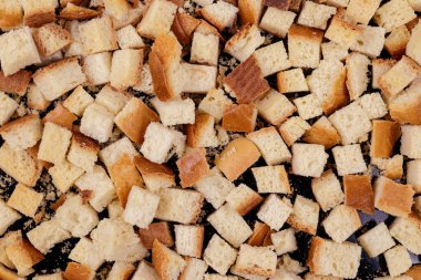 Koyu arkaplanda kavrulmuş beyaz ekmek parçaları. Lezzetli kızarmış ekmeklerin yakın çekimi..