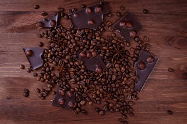 Kahve çekirdekleri ve baharatlarla ahşap bir masada fındıklı çikolata. Kızarmış kahve çekirdekleri ve anason yıldızları. Üst görünüm.