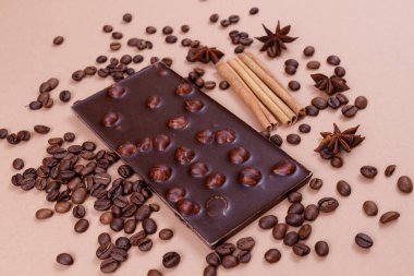 Bej arka planda fındıklı çikolata, kahve çekirdekleri ve baharatlar. Kavrulmuş kahve çekirdekleri, tarçın çubukları ve anason yıldızları. Fındıklı çikolata.. 