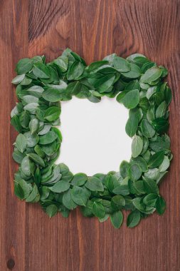 Ahşap zemin üzerinde kağıt not olan yapraklardan yapılmış yaratıcı bir çerçeve. Düz yatıyordu. Doğa konsepti. Süper manzara. Reklam kartı ya da davetiye için boşluk. 