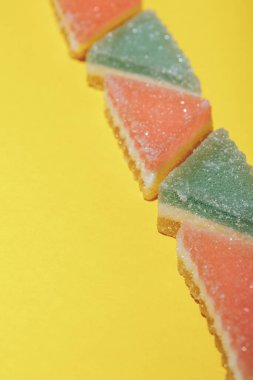 Sarı zemin üzerinde renkli üçgen jöle şekeri. 