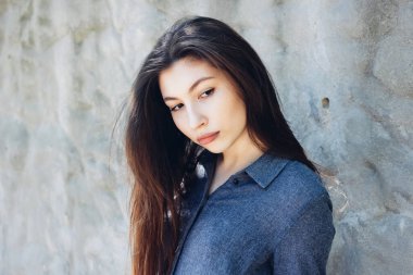 Güneşli bir günde beyaz beton duvarın önünde genç ve şık bir kızın portresi. Güzel bir kızın portresi. Uzun siyah saçlı ve kırmızı dudaklı güzel bir kız.. 