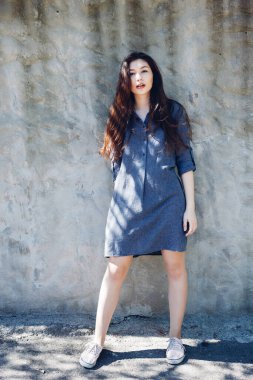 Güneşli bir günde beyaz beton duvarın önünde duran şık bir kız. Uzun siyah saçlı ve kırmızı dudaklı güzel bir kız.. 