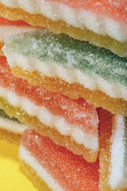 Çok renkli marmelatlı reçelli şekerler. Sarı arka planda üçgen marmelat şekeri yığını. Macro, seçici odaklanma.