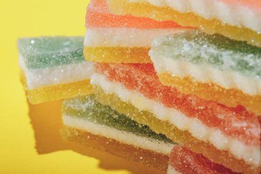 Çok renkli marmelatlı reçelli şekerler. Sarı arka planda üçgen marmelat şekeri yığını. Macro, seçici odaklanma.