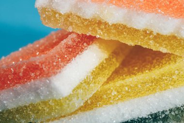 Çok renkli marmelatlı reçelli şekerler. Mavi arka planda üçgen marmelat şekeri yığını. Macro, seçici odaklanma.