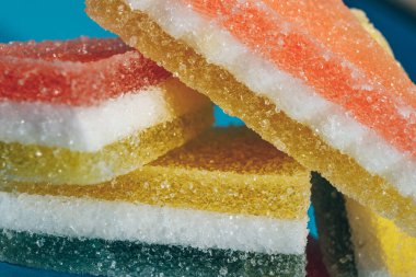 Çok renkli marmelatlı reçelli şekerler. Mavi arka planda üçgen marmelat şekeri yığını. Macro, seçici odaklanma.