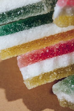 Çok renkli marmelatlı reçelli şekerler. Bej arka planda üçgen marmelat şekeri yığını. Macro, seçici odaklanma.