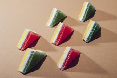 Kahverengi arka plana dizilmiş renkli üçgen jöle şekerler..