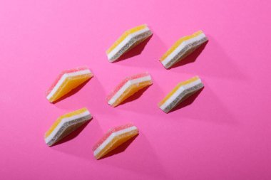 Pembe arka planda dizilmiş renkli üçgen jöle şekerler..