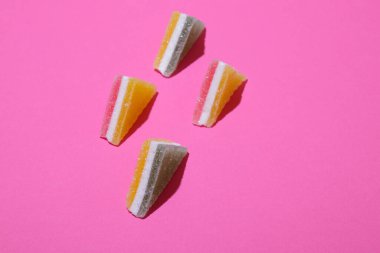 Pembe arka planda dizilmiş renkli üçgen jöle şekerler..