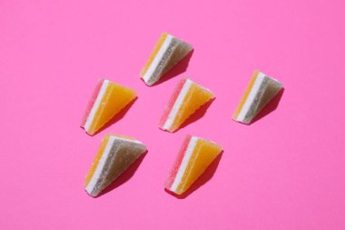 Pembe arka planda dizilmiş renkli üçgen jöle şekerler..