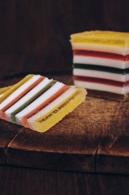 Ahşap masada dilimlenmiş çizgili marmelat. Renkli jöleli şekerler yakın plan..