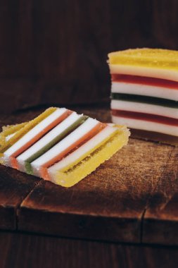 Ahşap masada dilimlenmiş çizgili marmelat. Renkli jöleli şekerler yakın plan..