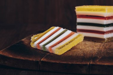 Ahşap masada dilimlenmiş çizgili marmelat. Renkli jöleli şekerler yakın plan..