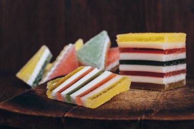 Ahşap masada dilimlenmiş çizgili marmelat. Renkli jöleli şekerler yakın plan..