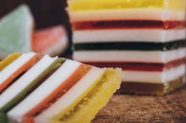 Ahşap masada dilimlenmiş çizgili marmelat. Renkli jöle şekerleri yakın plan. Makro çekim, seçici odaklanma.