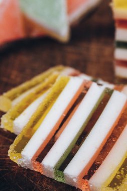 Ahşap masada dilimlenmiş çizgili marmelat. Renkli jöle şekerleri yakın plan. Makro çekim, seçici odaklanma.
