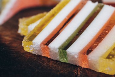 Ahşap masada dilimlenmiş çizgili marmelat. Renkli jöle şekerleri yakın plan. Makro çekim, seçici odaklanma.