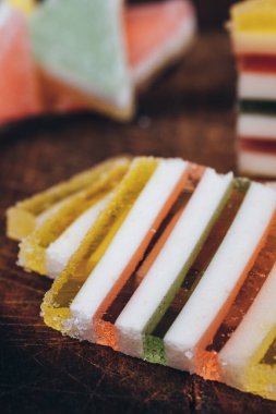 Ahşap masada dilimlenmiş çizgili marmelat. Renkli jöle şekerleri yakın plan. Makro çekim, seçici odaklanma.