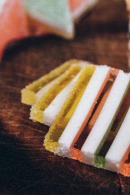 Ahşap masada dilimlenmiş çizgili marmelat. Renkli jöle şekerleri yakın plan. Makro çekim, seçici odaklanma.