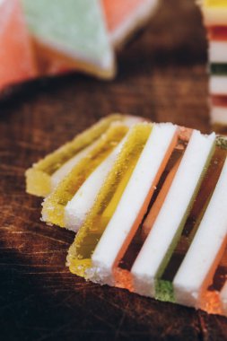Ahşap masada dilimlenmiş çizgili marmelat. Renkli jöle şekerleri yakın plan. Makro çekim, seçici odaklanma.