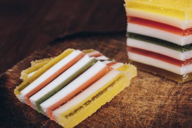 Ahşap masada dilimlenmiş çizgili marmelat. Renkli jöleli şekerler yakın plan..