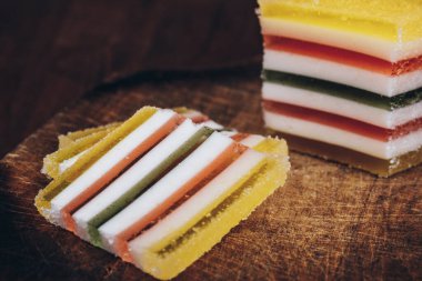 Ahşap masada dilimlenmiş çizgili marmelat. Renkli jöleli şekerler yakın plan..