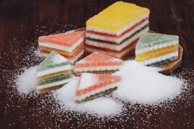 Çok renkli marmelatlı reçelli şekerler. Bir yığın üçgen ve dikdörtgen marmelat şekerle kaplı ahşap zemin.