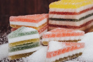 Çok renkli marmelatlı reçelli şekerler. Bir yığın üçgen ve dikdörtgen marmelat şekerle kaplı ahşap zemin.