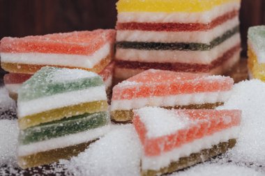 Çok renkli marmelatlı reçelli şekerler. Bir yığın üçgen ve dikdörtgen marmelat şekerle kaplı ahşap zemin.