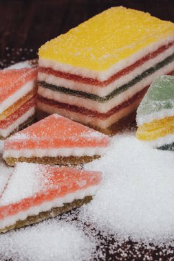 Çok renkli marmelatlı reçelli şekerler. Bir yığın üçgen ve dikdörtgen marmelat şekerle kaplı ahşap zemin.