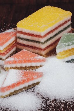 Çok renkli marmelatlı reçelli şekerler. Bir yığın üçgen ve dikdörtgen marmelat şekerle kaplı ahşap zemin.