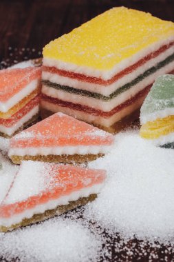 Çok renkli marmelatlı reçelli şekerler. Bir yığın üçgen ve dikdörtgen marmelat şekerle kaplı ahşap zemin.