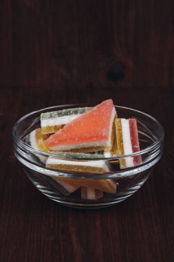 Ahşap arka plandaki cam kasede renkli jöle şekeri. Çok renkli marmelatlı reçelli şekerler. Bir yığın marmelat şekeri..