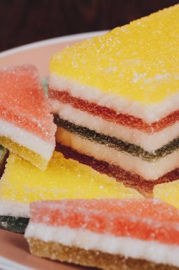 Ahşap arka plandaki tabakta renkli jöle şekeri. Çok renkli marmelatlı reçelli şekerler. Bir yığın üçgen ve dikdörtgen marmelat şekeri.