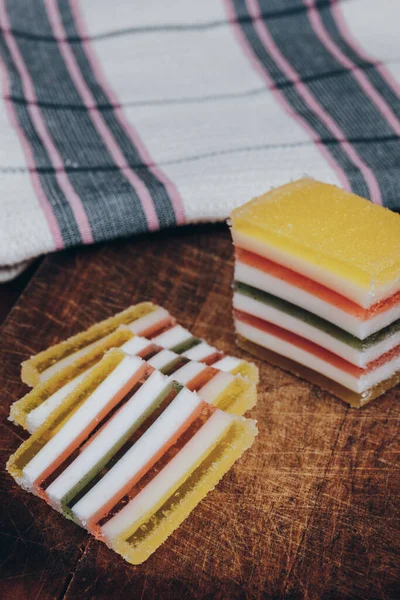 Ahşap masada dilimlenmiş çizgili marmelat. Renkli jöleli şekerler yakın plan..