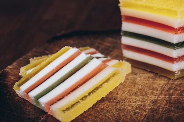 Ahşap masada dilimlenmiş çizgili marmelat. Renkli jöleli şekerler yakın plan..