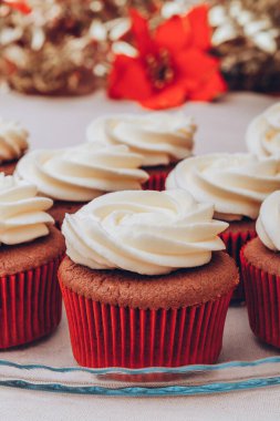 Üstünde krema olan enfes çikolatalı kekler. Renkli tatil geçmişi olan cam tepside kekler..