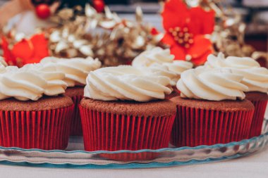 Üstünde krema olan enfes çikolatalı kekler. Renkli tatil geçmişi olan cam tepside kekler..