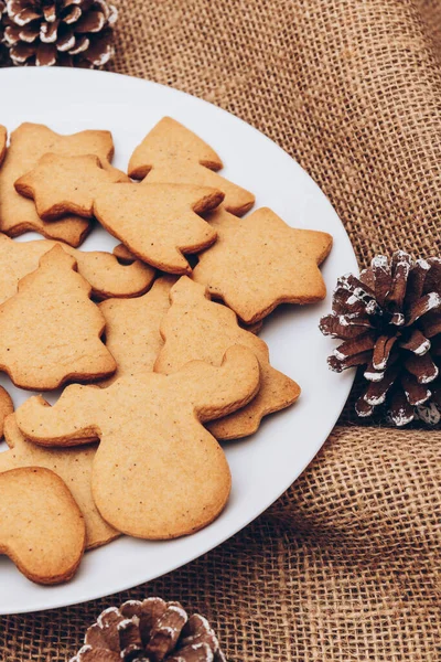 おいしいクリスマスジンジャーブレッドクッキー白いプレート上のサックスクロス — ストック写真