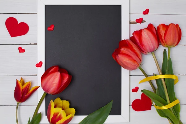 Tiza negra limpia vacía con tulipanes y corazones rojos. Vista superior . — Foto de Stock