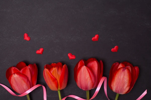 Lavagna nera pulita vuota con tulipani rossi e cuori. Vista dall'alto . — Foto Stock