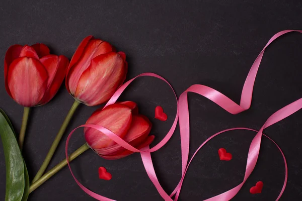 Lavagna nera pulita vuota con tulipani rossi e cuori. Vista dall'alto . — Foto Stock