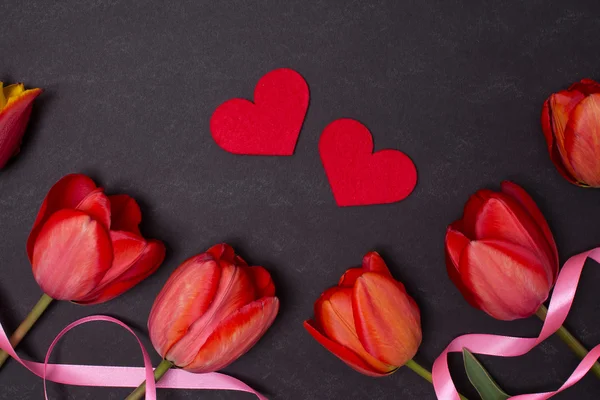 Порожня чиста чорна дошка з червоними тюльпанами та сердечками. Вид зверху . — стокове фото